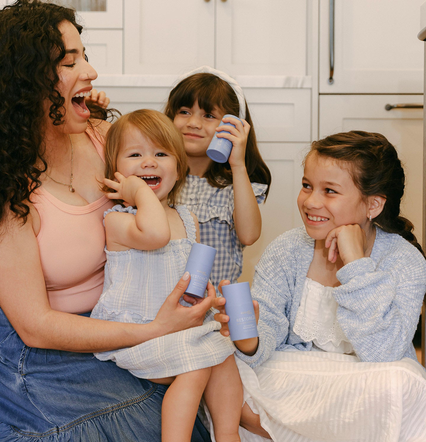 Mom and three daughters laughing together and holding RESTORE24 bottles