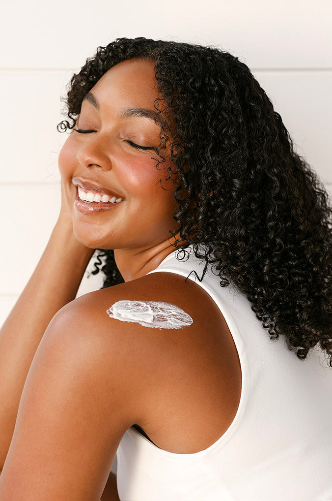 Woman with RESTORE24 cream on her shoulder with a white background