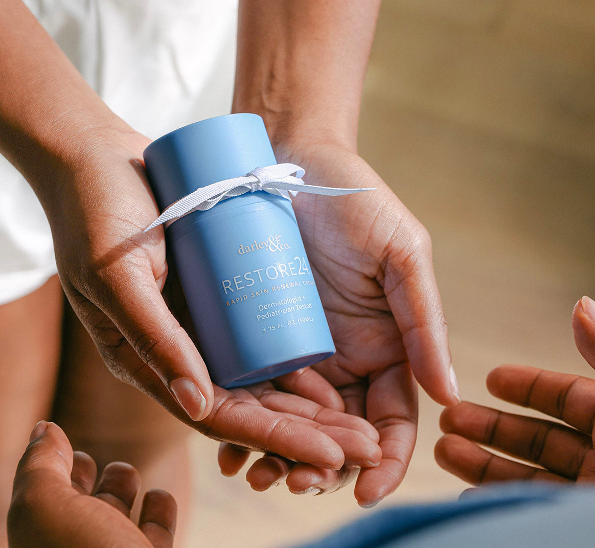Blue RESTORE24 bottle with ribbon held in hands with a blurred background