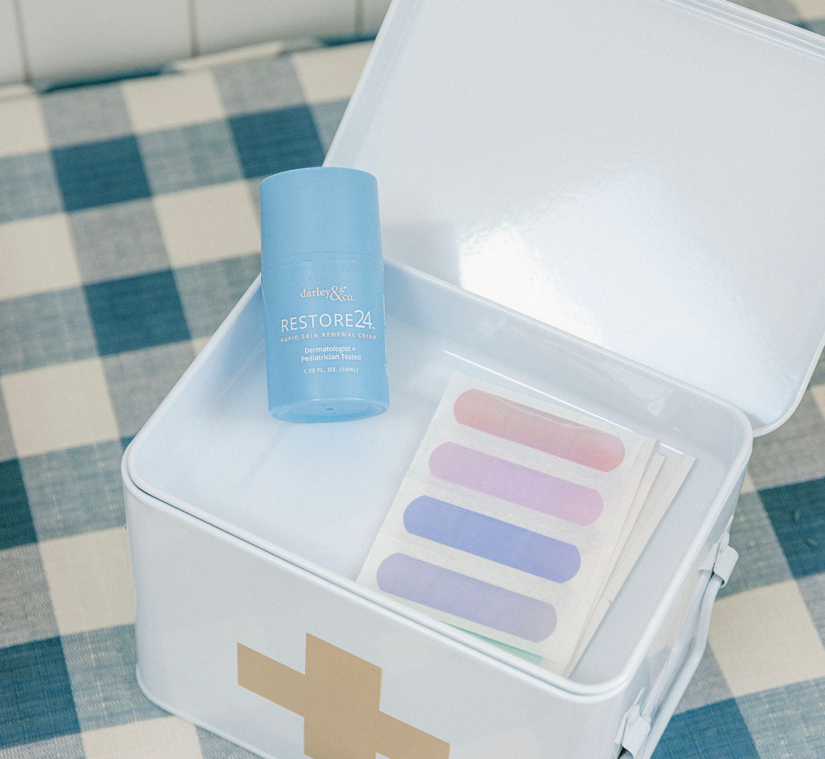 Blue RESTORE24 bottle in a white first-aid box with gold cross symbol on a checkered floor.